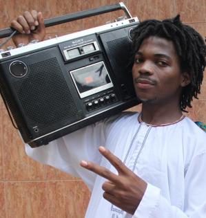 Hiphopperen Burney Mc med boombox og den arabiske kjorteldragt "Kanzu", som er blevet populær i det ugandiske hiphopmiljø. Både dragt og boombox er del af den nye UNESCO Samling fra Uganda.